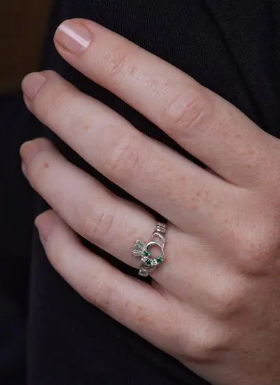Close up of model's hand wearing Sterling Silver Claddagh Ring with Green Cubic Zirconia